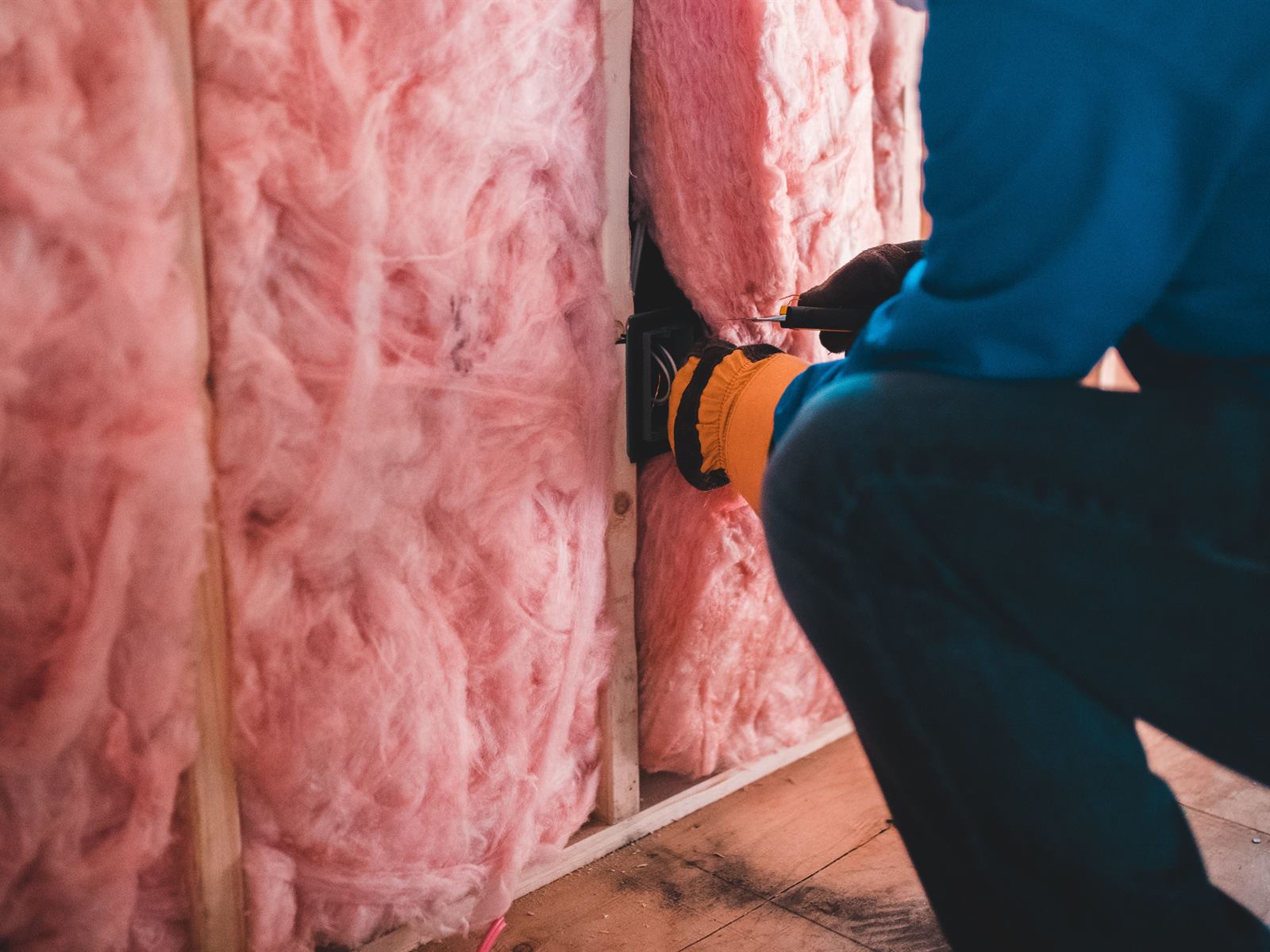 Handwerker setzt Dämmung zwischen die Ständer einer Holzwand