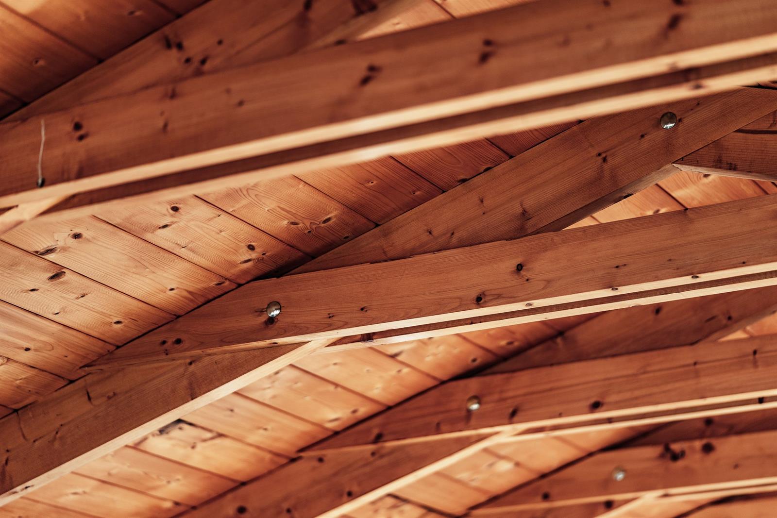Sichtdachstuhl aus Holz mit warm beleuchteten Sparren und Pfetten