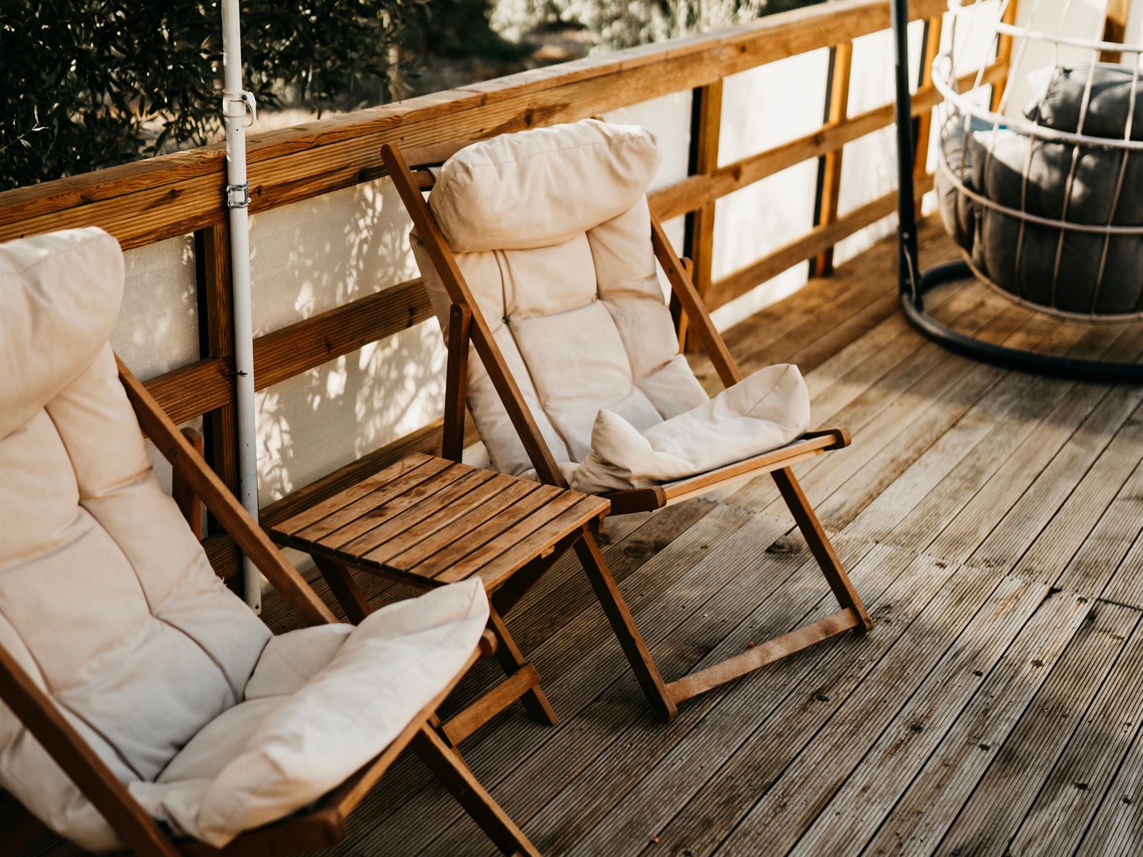 Holzterrasse mit Dielenbelag, Holzgeländer und zwei Liegestühlen